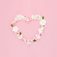 Spring flowers sakura in the shape of heart on pink background. Template for wedding invitation or greeting card for Valentine's Day. Copy space