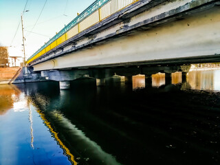 Transport bridge over the river in the city with yellow-blue railings, side view