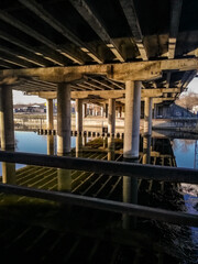 View under the bridge over the river on a row of pillars in perspective supporting the bridge.