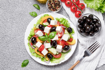Greek salad with cheese and fresh vegetables on grey background. Flat lay, top view, copy space