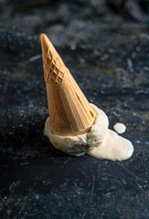 Fallen ice cream upside down on dark concrete