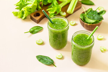 Vegan smoothie recipe. Healthy diet and nutrition, vegan and alkaline drink. Green fresh smoothie with celery and spinach on a pink background. Copy space.