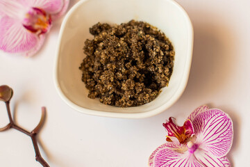 Plate of scrub wiht roses on white orcgids, top view. image of homemade cosmetics ingredients. aroma theme. organic cosmetics.