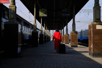 A young girl in a red coat goes to the platform of the railway station