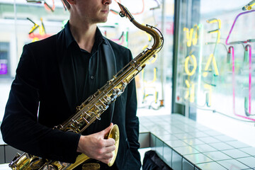 Fototapeta na wymiar saxophone in hands close-up man in black outfit