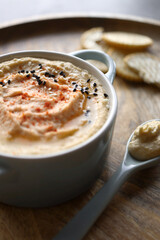 Hummus with light and dark sesame seeds and crackers in the background