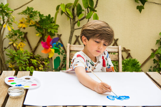 Watercolor Painting Outdoors.
Children Doing Watercolor Artwork Outdoors For Homeschool Art. 
Young Boy Learning To Paint With Watercolor Crayons. Hobbies And Entertainment.