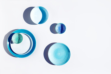 Blue ceramic bowls and plates on white background top view. Colorful ceramic empty dishes with hard shadows.