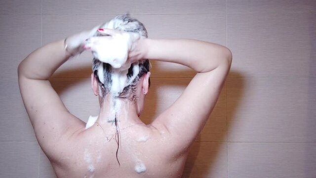 Woman washes her hair with shampoo in the shower with, hair care, ceratin mask, rinse shampoo and balm, strong hair, washing hair