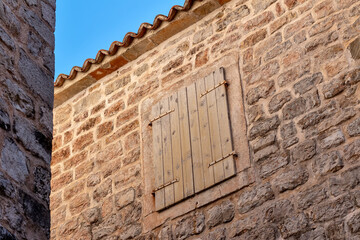 Window with closed shutters on the stone wall of an old house