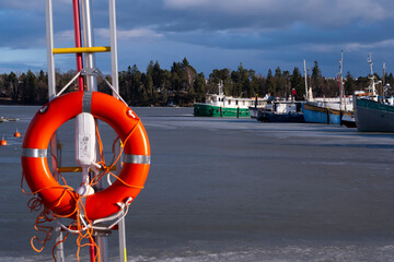 A spring scene of a small leisure boat harbor with orange lifesaver in the foreground.