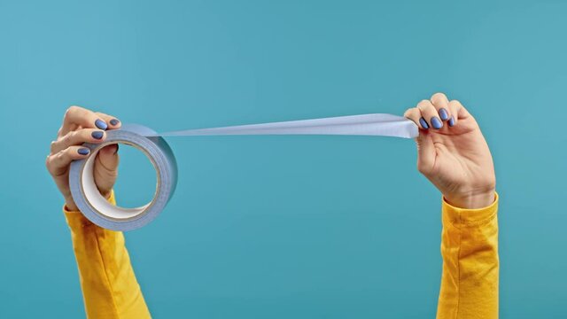 Female hands with adhesive tape on a blue background. Useful home gadget.
