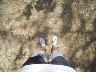 POV shot. Male runner looking down at his feet, standing on dirty road, ready for run.