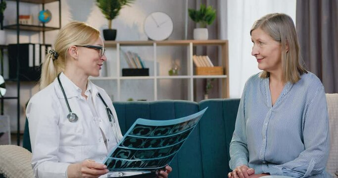 Likable positive skilled blond woman-doctor is satisfied from result of x-ray scan of patient and giving high five with patient during visiting her at home,healthcare concept