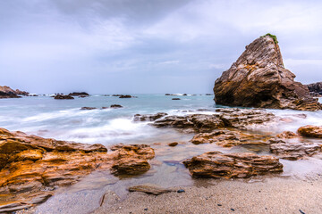 Piedras color marrón anaranjado en la playa con la marea baja. Así es la costa de Galicia