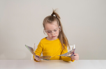 Laboratory, chemical experiments day 1 of 14. a girl in plastic goggles, holds a magazine with her...
