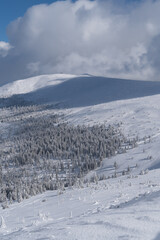 Fototapeta premium Winter mountain landscape, Poland, Panorama of the Giant Mountains in sunny winter day, from Biała Dolina in Szklarska Poreba on Szrenica and Sniezne Kotly, blue sky, white and dark clouds. Snow cover