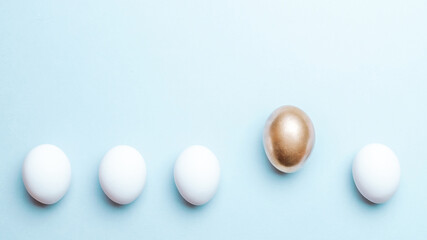 Easter background blue. Golden, white colour egg on pastel blue background in Happy Easter decoration. Flat lay, top view.