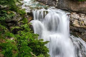 Fototapeta na wymiar Fotografía de larga exposición que permite hacer sedosas las aguas de un arroyo que forman una pequeña cascada en el Parque Nacional de Ordesa y Monte Perdido, en los Pirineos españoles