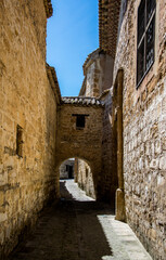 Fototapeta na wymiar Un arco de piedra que conecta dos casas solariegas medievales en el casco histórico de Baeza, España, reconocido en la lista del Patrimonio Mundial de la UNESCO