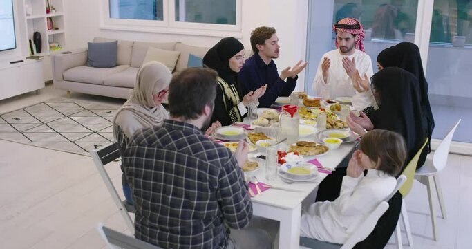 Eid Mubarak Muslim people praying before iftar dinner. Eating traditional food during Ramadan feasting month at home. 