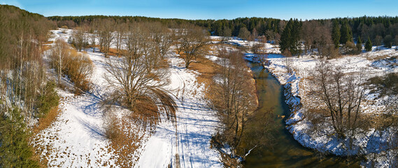 Dirt rural road, wood, ice and snow panorama. Islach river aerial view, Belarus