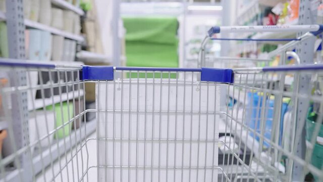 POV of shopping cart moving through supermarket household aisle, close up mall trolley grid view with background of hardware store, relaxing activity on weekend, marketing sale promotion or discount