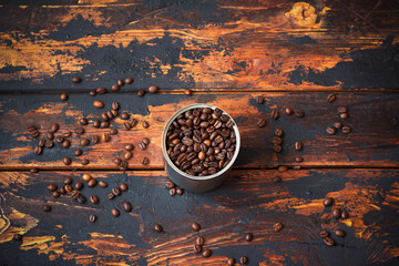 Blended coffee beans in a tin can on a rustic wooden table among scattered coffee beans, blended, vintage, top view