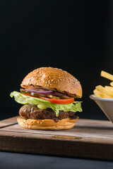 Freshly cooked organic marble beef burger, cheeseburger with fresh farm vegetables, onion, salad leaves, tomatoes, bbq sauce, french fries served as a main dish in a fancy restaurant during lunchtime