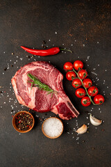 raw  ribeye steak with spices on a stone background