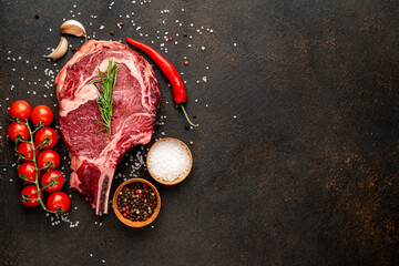 raw ribeye steak with spices on stone background with copy space for your text