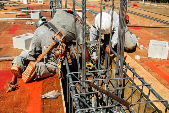 Workers tying rebar together on a large grade beam