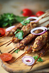 Lula kebab with onions, lavash and herbs on a wooden board. Ramadan dish. Turkish or Arabic food.