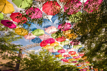 Colorful floating umbrellas hang above the street. Umbrella Sky Project in Coral Gables, Miami,...