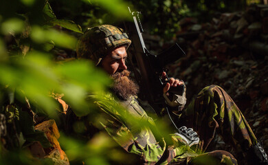 Soldier with sad face in military helmet and camouflage with gun