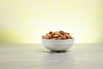 Pile of almond nuts in the glass bowl on the wooden table 