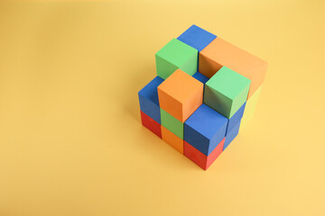 Colorful cubes stacked and isolated on the yellow background 