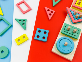 Multicolored wooden blocks on red blue background. Trendy puzzle toys. Geometric shapes: square, circle, triangle, rectangle. Educational toys for kindergarten, preschool or daycare. Back to school	
