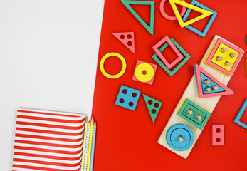 Multicolored wooden blocks on red background. Trendy puzzle toys. Geometric shapes: square, circle, triangle, rectangle. Educational toys for kindergarten, preschool or daycare. Back to school	