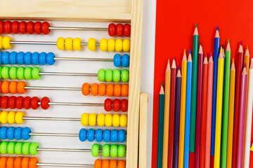 Multicolored wooden pencils and abacus on red background. Trendy puzzle toys. Educational toys for...