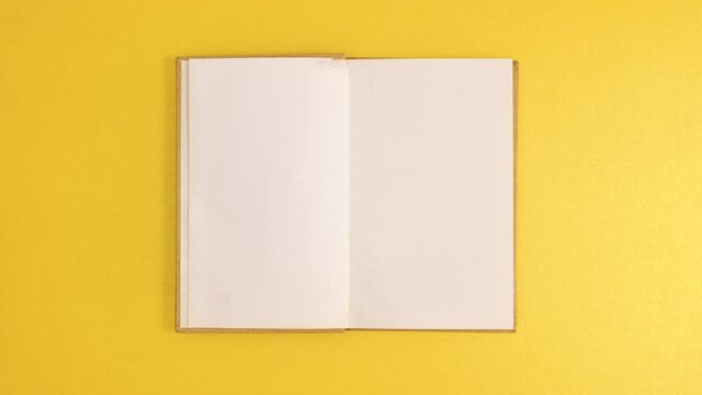 Golden vintage hardcover book appear and open with copy space on golden background. Stop motion flat lay