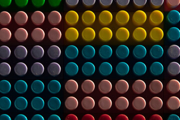 childish game background: darkened plane of plastic multi-colored bricks, blur, selective focus