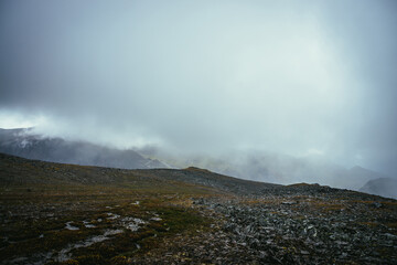 Dark atmospheric landscape on edge of abyss in highlands. Dangerous mountains and abyss among low clouds. Danger mountain pass and sharp rocks in clouds. Dangerous cloudy rainy weather in mountains.