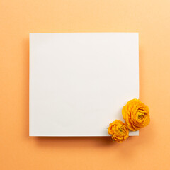 Blank memo pad with dry flowers on orange background. top view, copy space