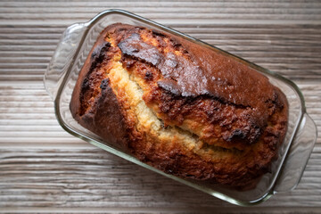Freshly baked loaf of banana nut bread in a glass dish on a wood table