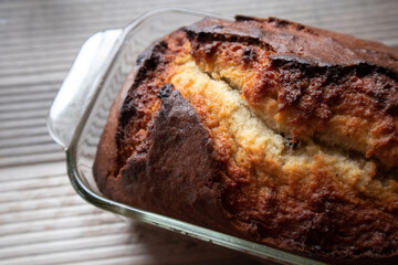 Freshly baked loaf of banana nut bread in a glass dish on a wood table