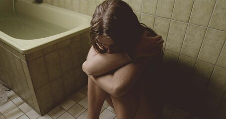 Depressed Woman Hugging Self In Bathroom
