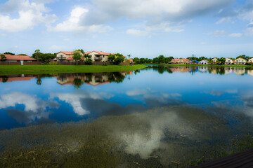 Lake waterfront houses and sky reflection at a Kendall Lakes neighborhood during a cloudy summer...
