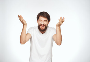 Happy man gestures with his hands on a white background in a light T-shirt