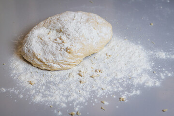 Homemade dough covered with powder on the table.